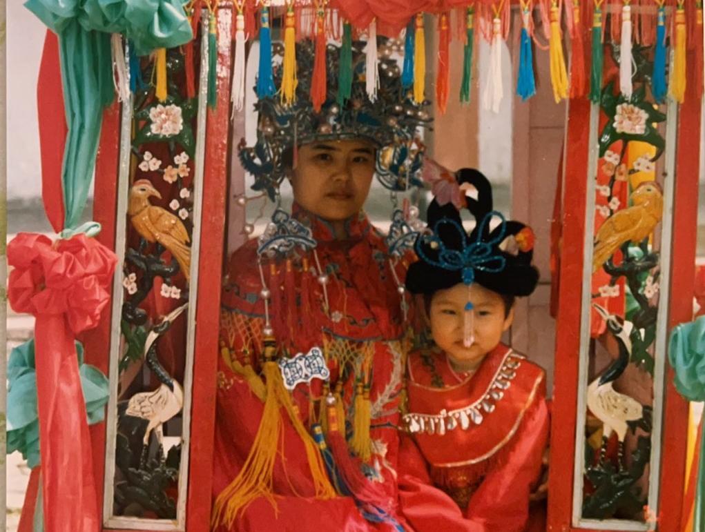 杨小姐小时候穿着传统服装和妈妈合影. 在中国文化中，红色被认为是幸运的颜色.